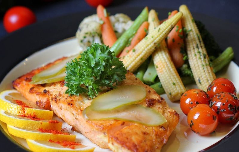 A beautifully plated salmon dish with fresh vegetables and lemon slices, perfect for a gourmet meal.