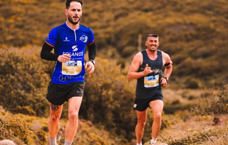 Dynamic image of two men trail running through an outdoor natural setting, showcasing energy and fitness.